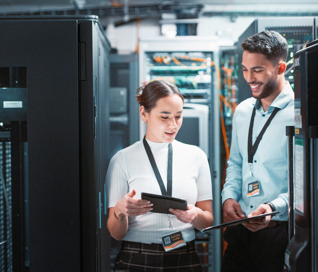 Zwei Personen arbeiten und besprechen sich in einem Datenzentrum. Das Bild wurde im Rahmen des Brandings für sämtliche Digitalisierungsmaßnahmen unseres Industriekunden eingesetzt.