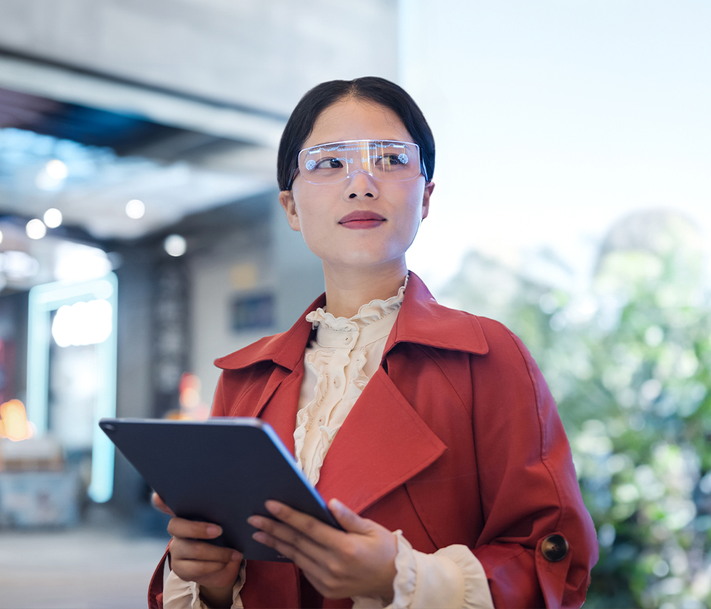 A woman with a tablet in her hand, wearing smart glasses and used as a visual in the artificial intelligence campaign.